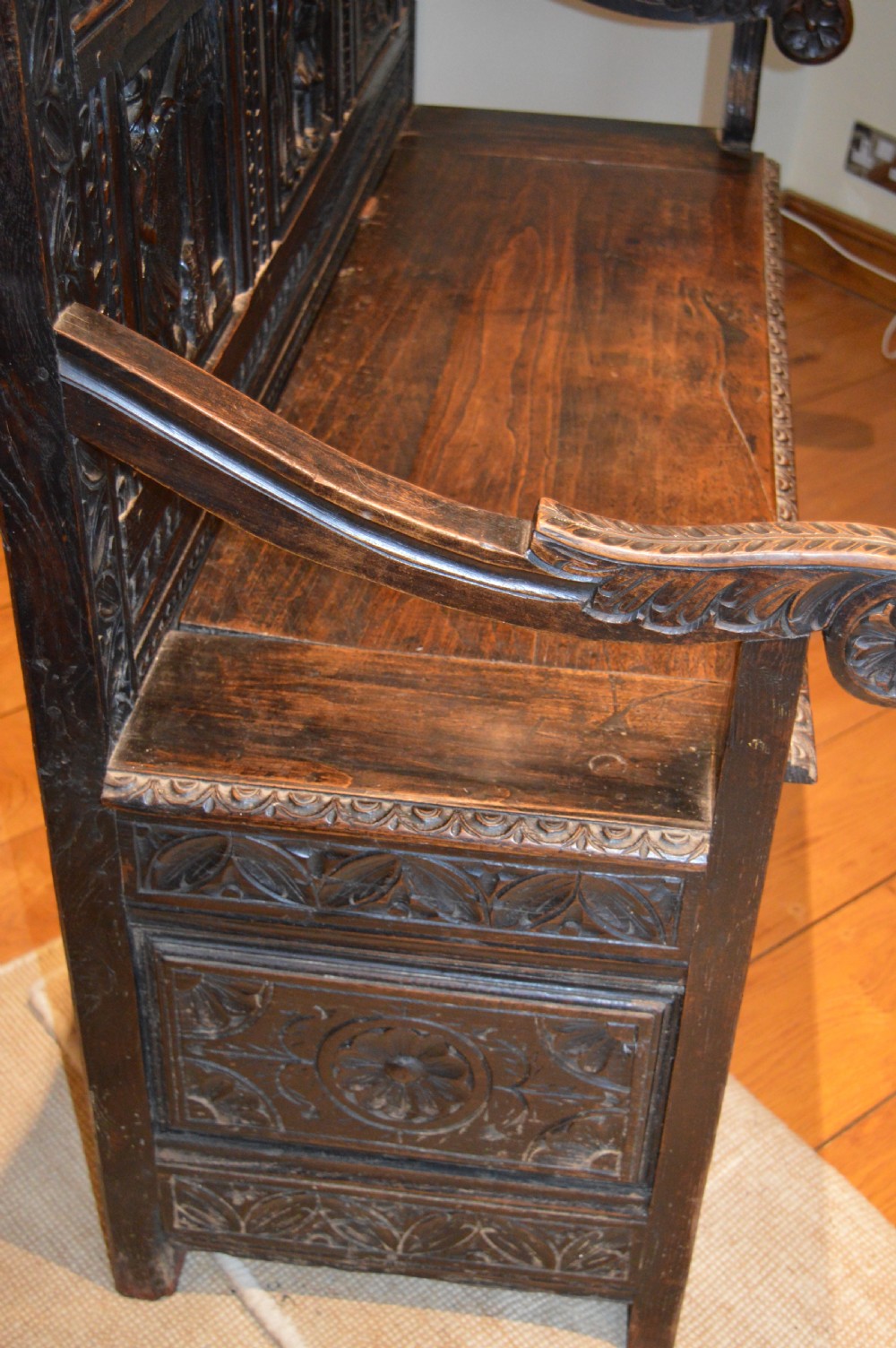 An 18th-century Flemish dark carved oak settle featuring figurative relief panels on the backrest and chest base with scrolled armrests. View XXII