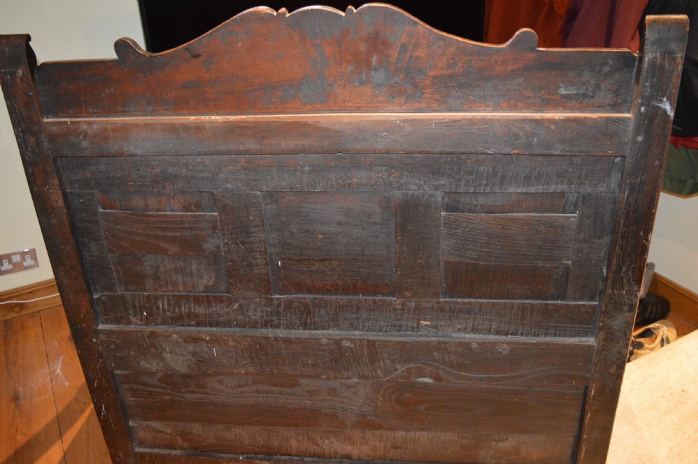 An 18th-century Flemish dark carved oak settle featuring figurative relief panels on the backrest and chest base with scrolled armrests. View XXIII