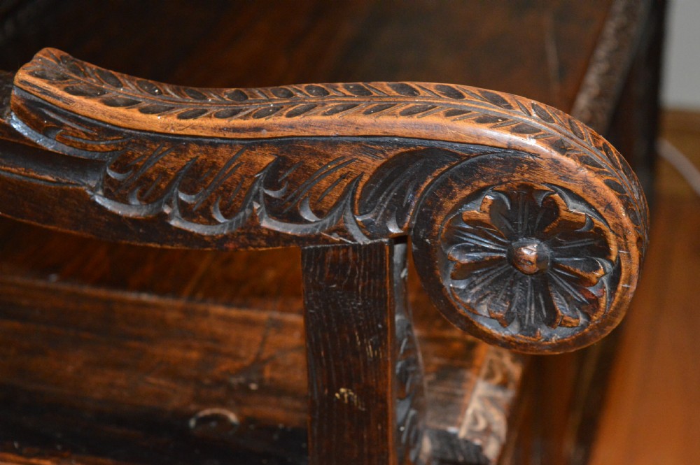 An 18th-century Flemish dark carved oak settle featuring figurative relief panels on the backrest and chest base with scrolled armrests. View XXIV