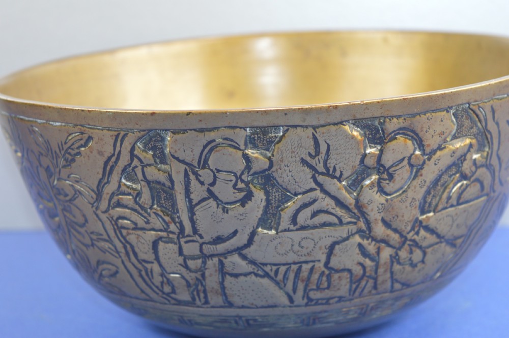 A large circular bronze bowl with relief engravings of figures in a landscape around the exterior and a polished interior. View II