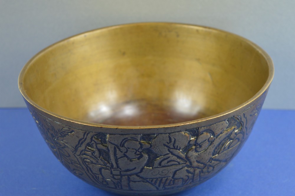 A large circular bronze bowl with relief engravings of figures in a landscape around the exterior and a polished interior. View III
