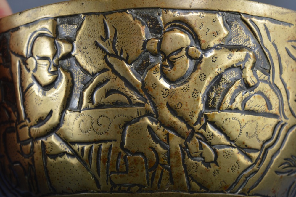A large circular bronze bowl with relief engravings of figures in a landscape around the exterior and a polished interior. View V