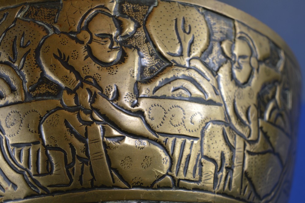 A large circular bronze bowl with relief engravings of figures in a landscape around the exterior and a polished interior. View X