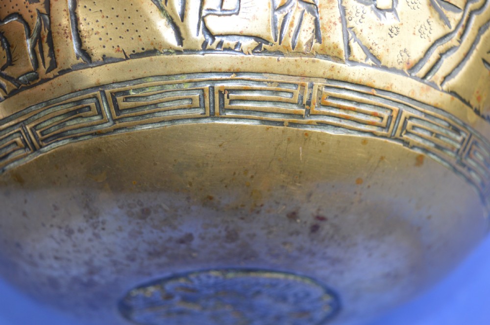 A large circular bronze bowl with relief engravings of figures in a landscape around the exterior and a polished interior. View XII