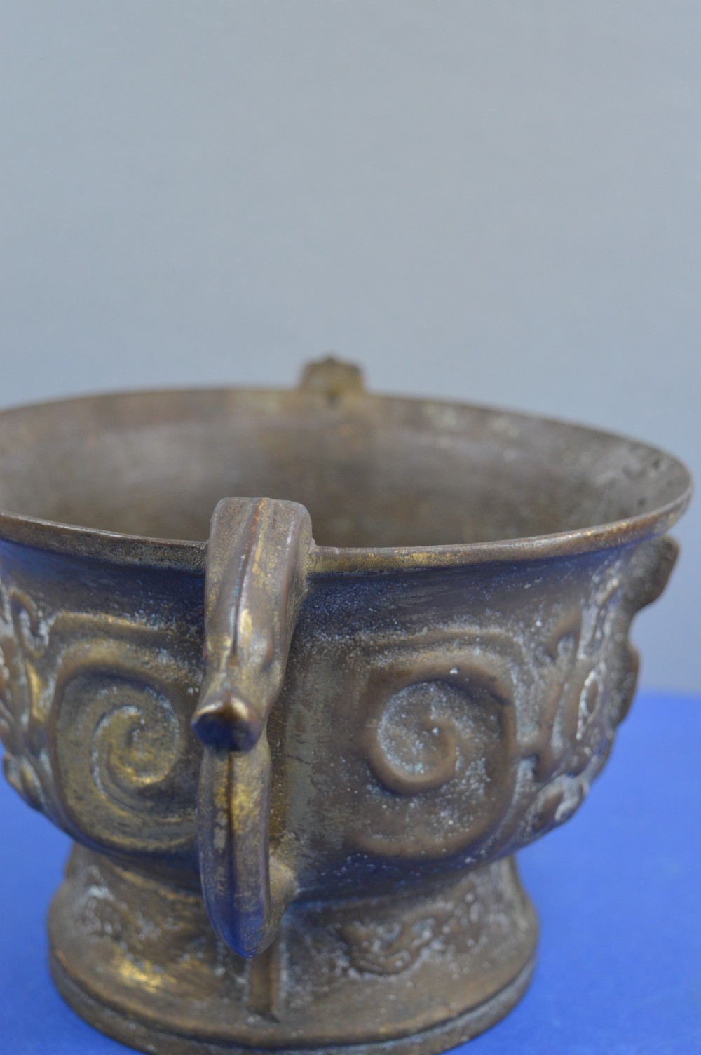 A cast bronze ritual food vessel with two loop handles topped with beast heads, featuring relief carvings and a raised circular base. View IX