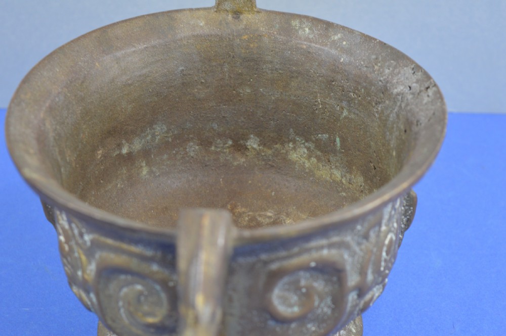 A cast bronze ritual food vessel with two loop handles topped with beast heads, featuring relief carvings and a raised circular base. View X