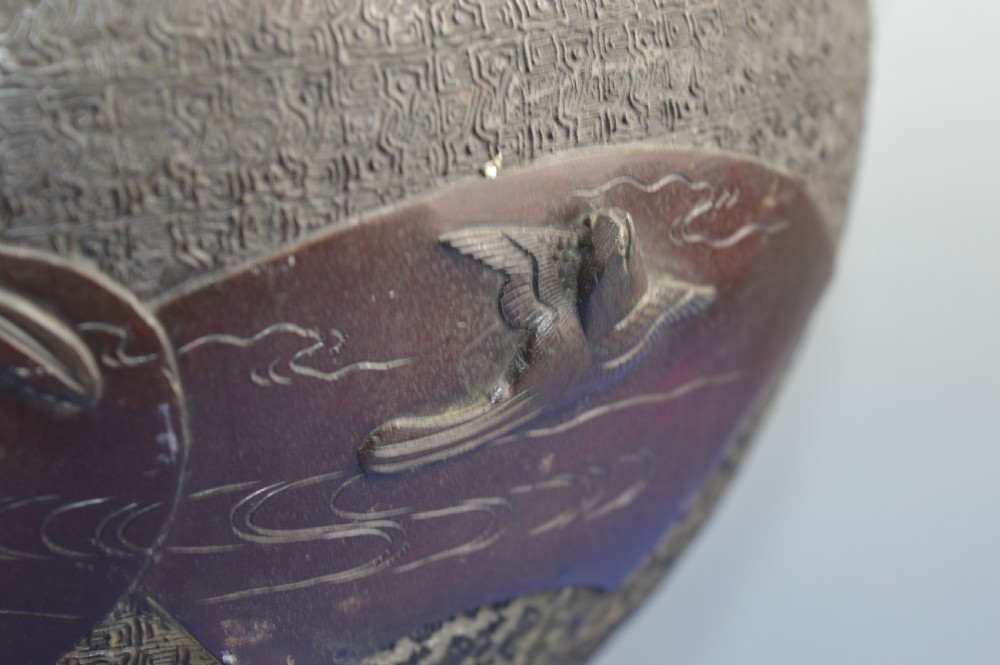 A heavy dark bronze Chinese bowl featuring relief panels with bird and floral motifs, bamboo-style side handles, and a lobed collar over an integral stepped base. View IV