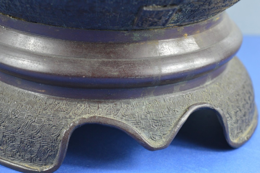 A heavy dark bronze Chinese bowl featuring relief panels with bird and floral motifs, bamboo-style side handles, and a lobed collar over an integral stepped base. View VI
