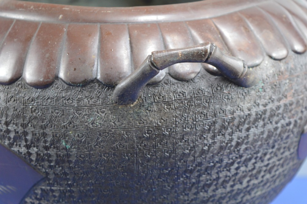 A heavy dark bronze Chinese bowl featuring relief panels with bird and floral motifs, bamboo-style side handles, and a lobed collar over an integral stepped base. View XVII
