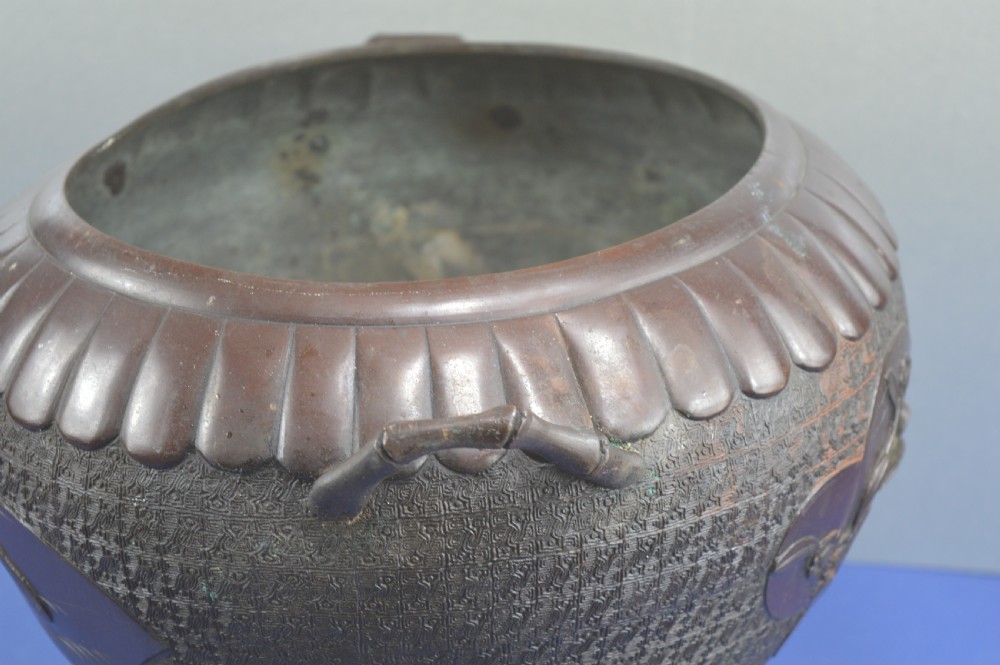 A heavy dark bronze Chinese bowl featuring relief panels with bird and floral motifs, bamboo-style side handles, and a lobed collar over an integral stepped base. View XIX