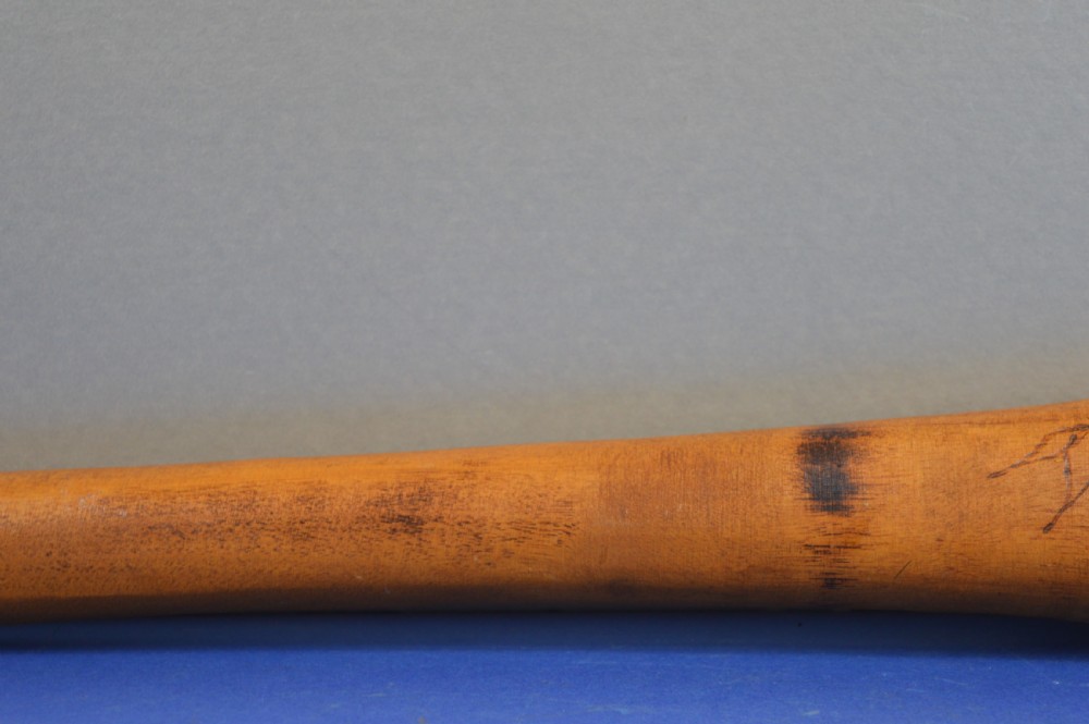 A carved light brown hardwood throwing club featuring a pointed bulbous head with pyrography markings and a smooth tapered shaft. View IV