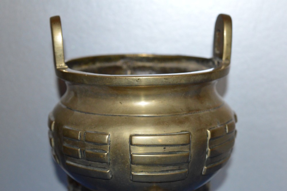 A late nineteenth-century Chinese cast bronze tripod censer featuring raised trigram motifs, upright loop handles, and beast-mask feet. View II