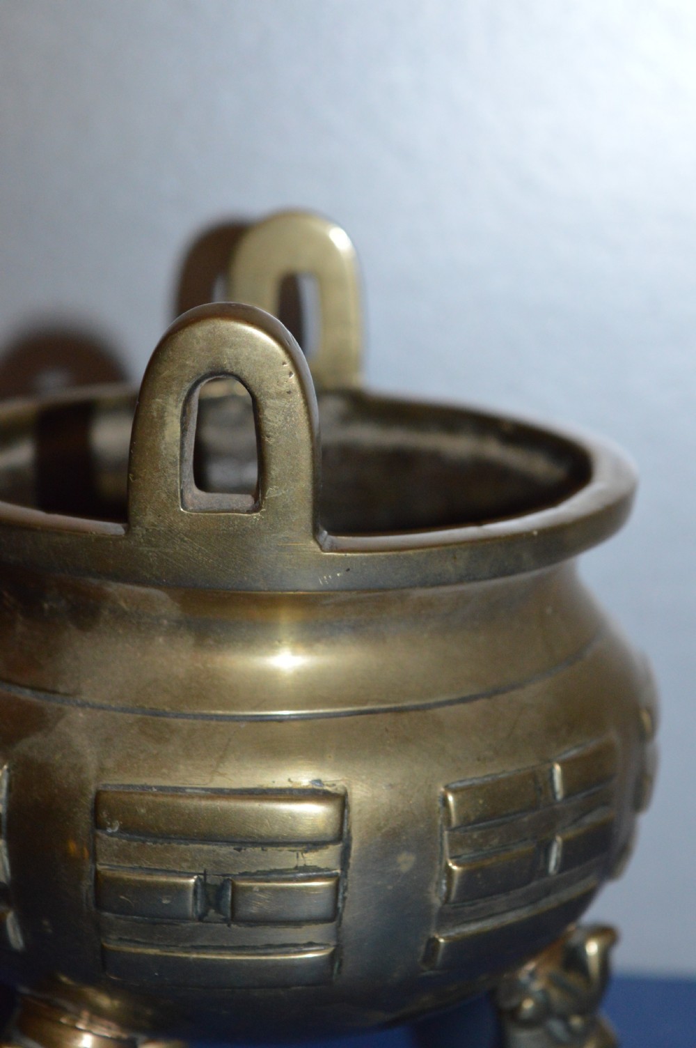 A late nineteenth-century Chinese cast bronze tripod censer featuring raised trigram motifs, upright loop handles, and beast-mask feet. View IV
