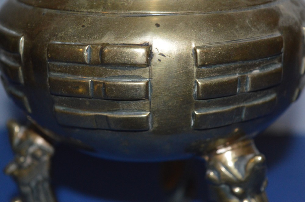 A late nineteenth-century Chinese cast bronze tripod censer featuring raised trigram motifs, upright loop handles, and beast-mask feet. View X