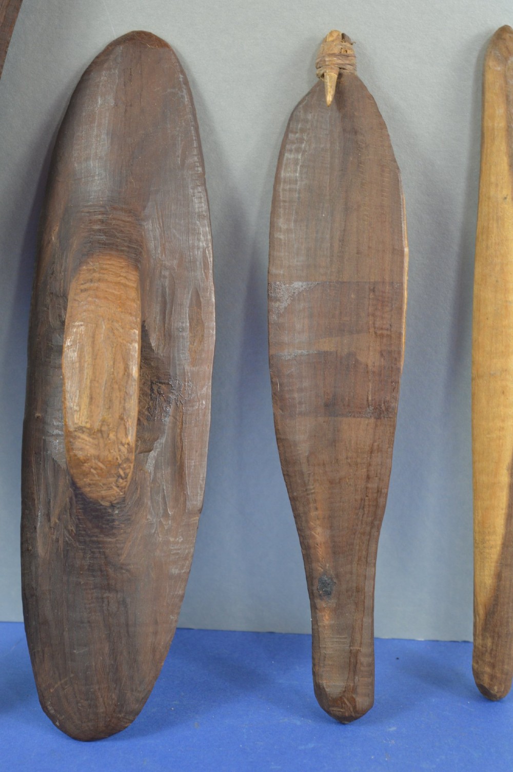 A four-piece set of dark hand-carved wooden Indigenous Australian hunting items, including a boomerang, small shield, spear thrower, and club. View II