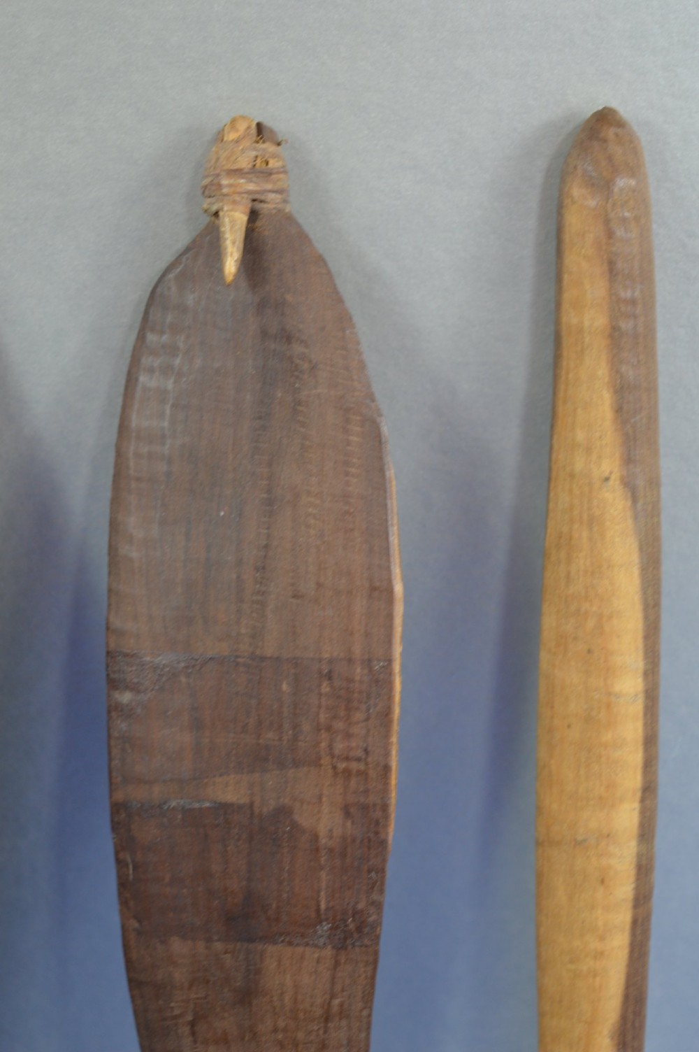 A four-piece set of dark hand-carved wooden Indigenous Australian hunting items, including a boomerang, small shield, spear thrower, and club. View V