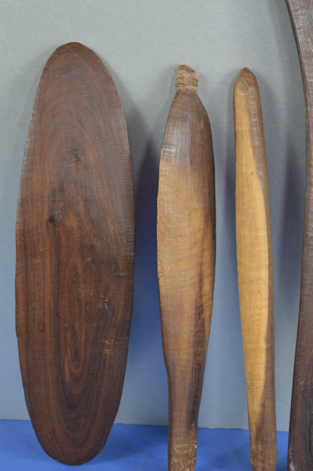 A four-piece set of dark hand-carved wooden Indigenous Australian hunting items, including a boomerang, small shield, spear thrower, and club. View VII