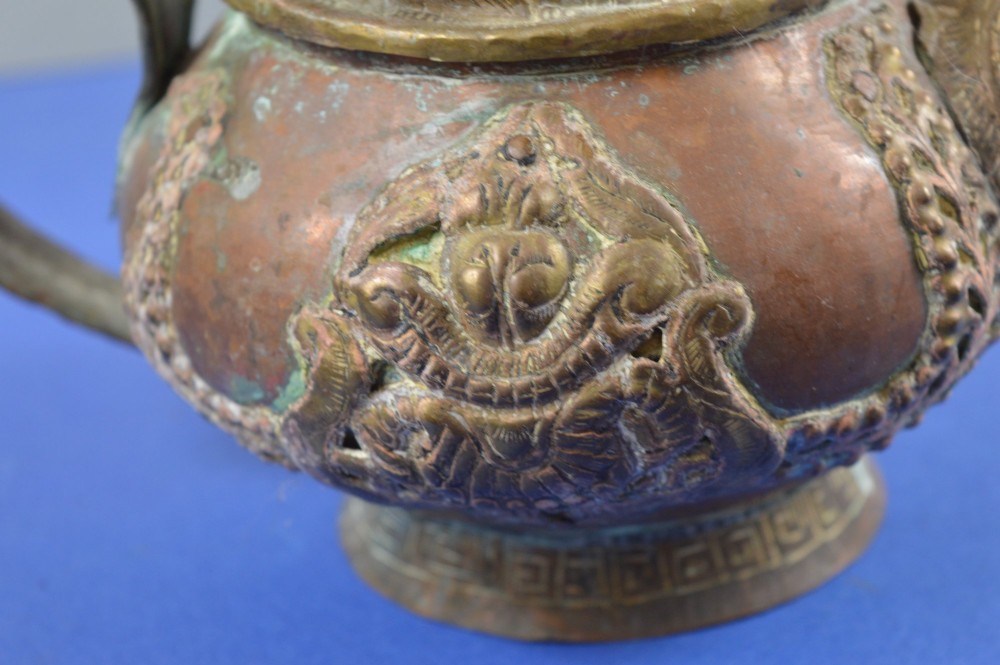 A pair of 19th-century Tibetan metal vessels comprising a squat copper pot with a snow lion lid and a tall cylindrical brass ewer with a dragon spout. View IV
