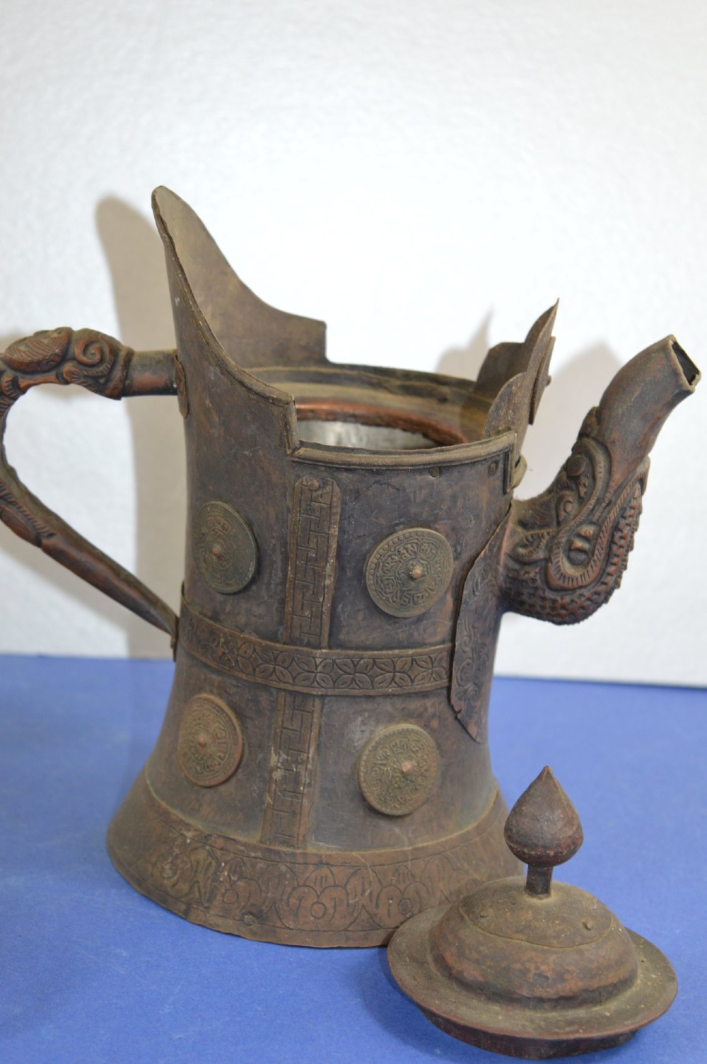 A pair of 19th-century Tibetan metal vessels comprising a squat copper pot with a snow lion lid and a tall cylindrical brass ewer with a dragon spout. View XII