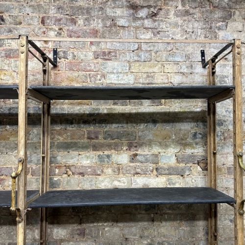 fig 1. A large 1920s industrial shelving unit featuring five tiers of dark grey slate slabs supported by a distressed cream painted iron framework.