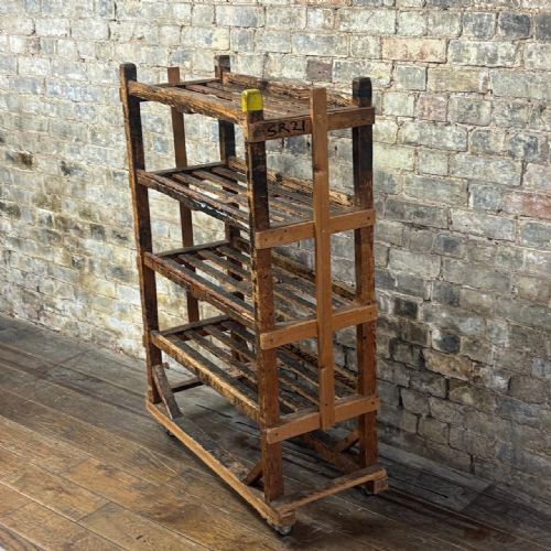 fig 1. A four-tiered early 20th-century wooden shoe trolley featuring slatted pine shelves, diagonal corner bracing, and metal swivel castors at the base.