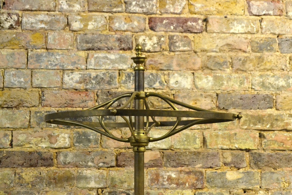 A freestanding Victorian coat stand featuring a circular brass hat rack crown, a central brass stem, and a heavy four-legged cast iron base. View II