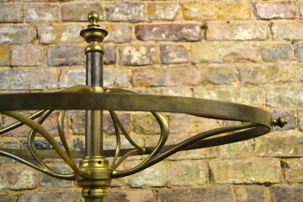 A freestanding Victorian coat stand featuring a circular brass hat rack crown, a central brass stem, and a heavy four-legged cast iron base. View V