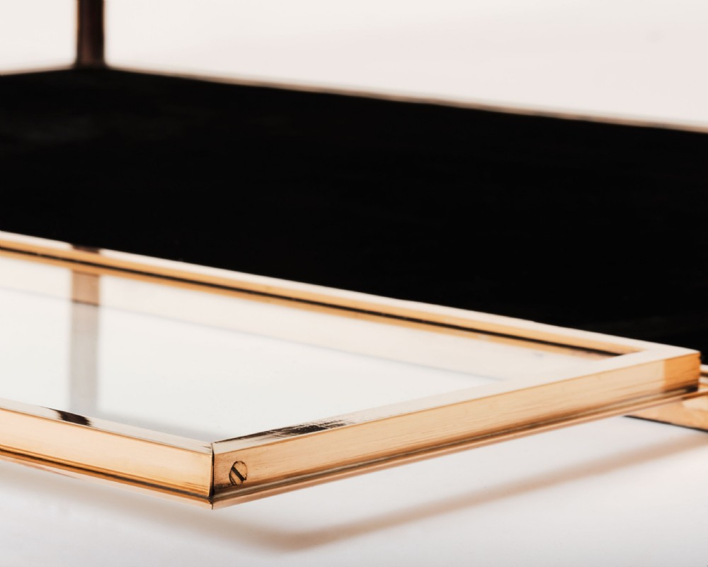 A rectangular clear glass display case with a brass frame and a black velvet-lined bottom surface. View II