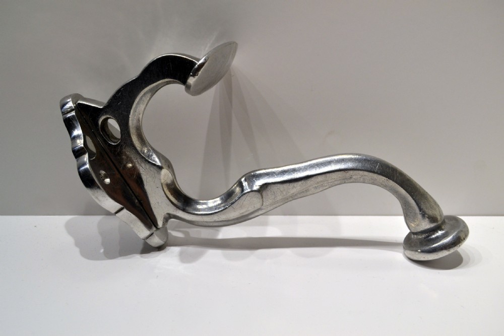 A set of three polished cast aluminium wall-mounted coat and hat hooks featuring shaped backplates and curved pegs. View III