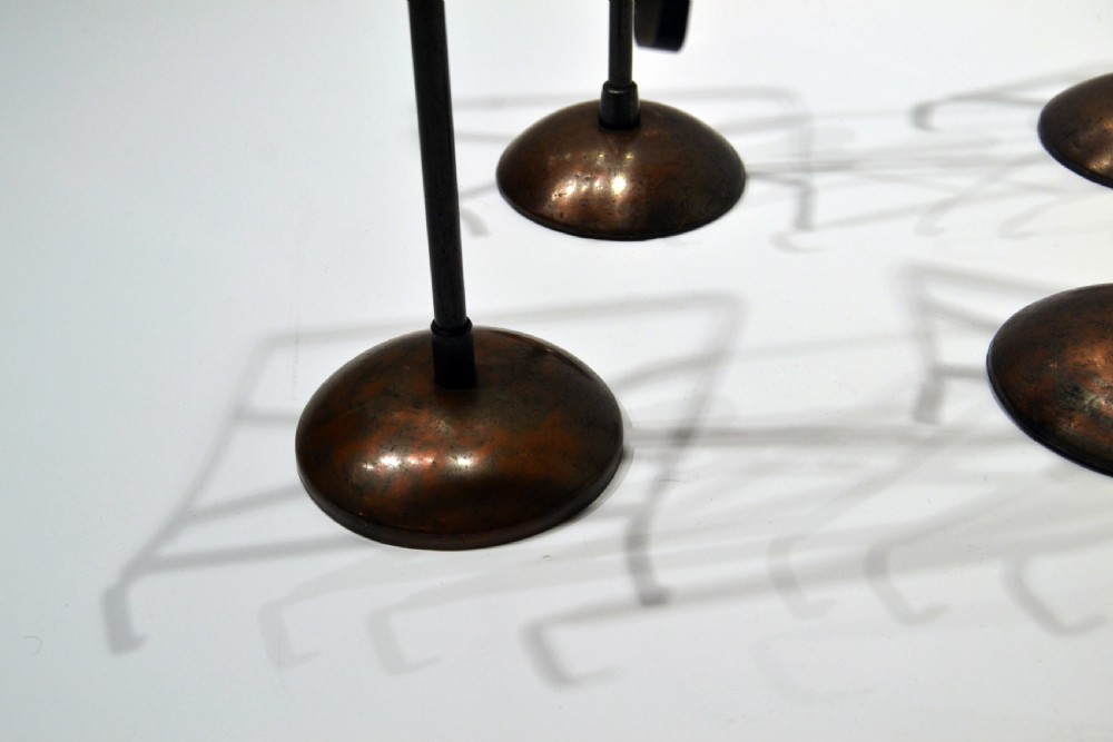 A set of four vintage 1930s adjustable metal shirt stands with circular weighted bases and geometric wire display frames. View II