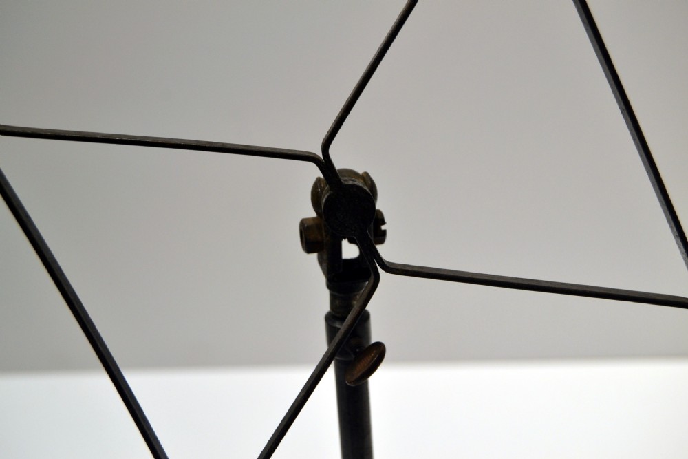 A set of four vintage 1930s adjustable metal shirt stands with circular weighted bases and geometric wire display frames. View V