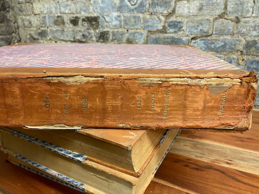 A large mid-20th-century bound archive volume of the Manchester Evening News featuring a tan leather spine with gilt lettering and marbled paper covers.