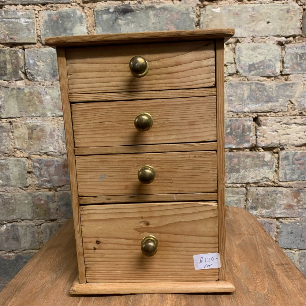 A small tabletop pine cabinet with four stacked drawers, each fitted with a round brass knob. View II