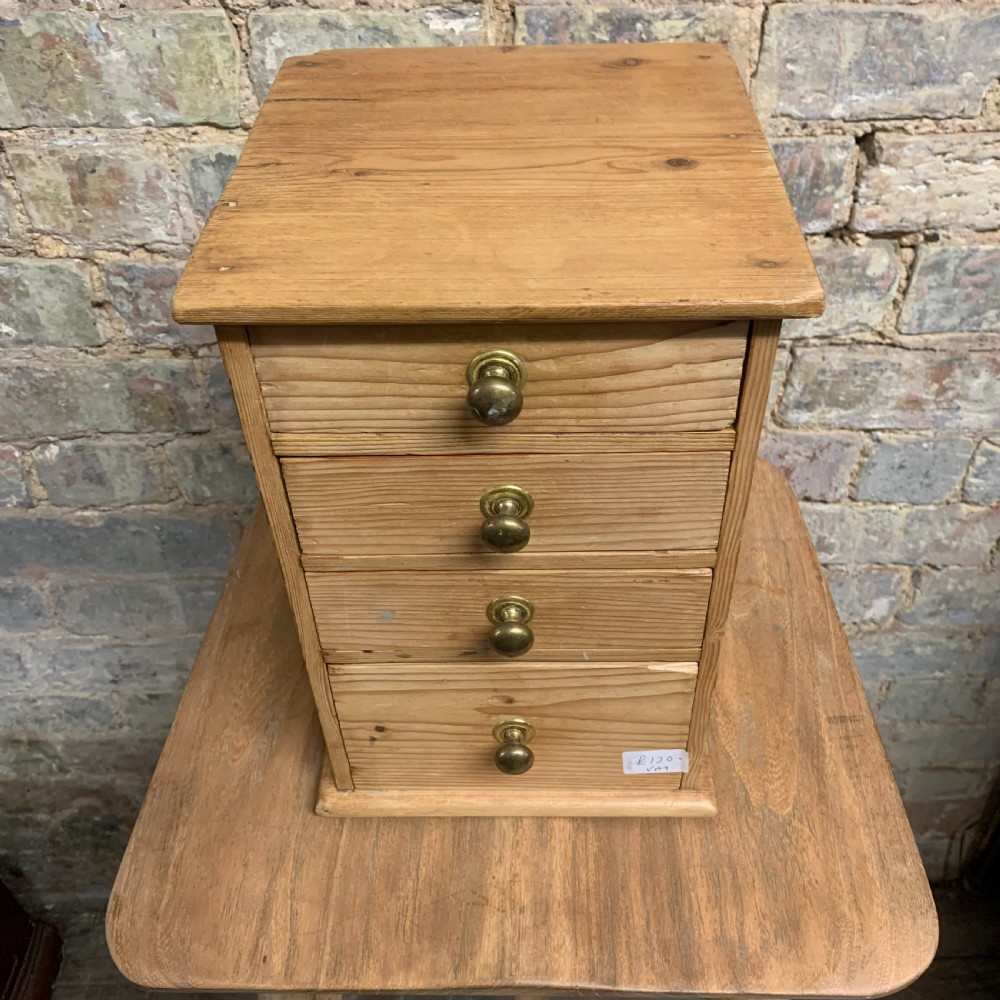 A small tabletop pine cabinet with four stacked drawers, each fitted with a round brass knob. View III