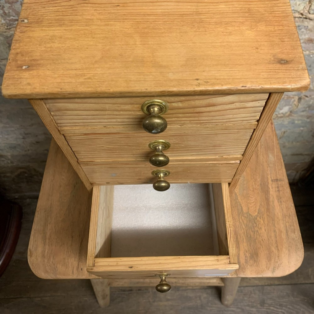 A small tabletop pine cabinet with four stacked drawers, each fitted with a round brass knob. View V