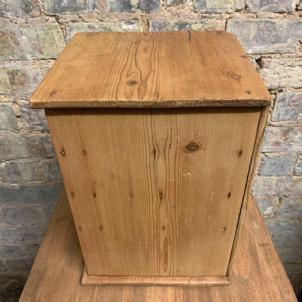 A small tabletop pine cabinet with four stacked drawers, each fitted with a round brass knob. View VI