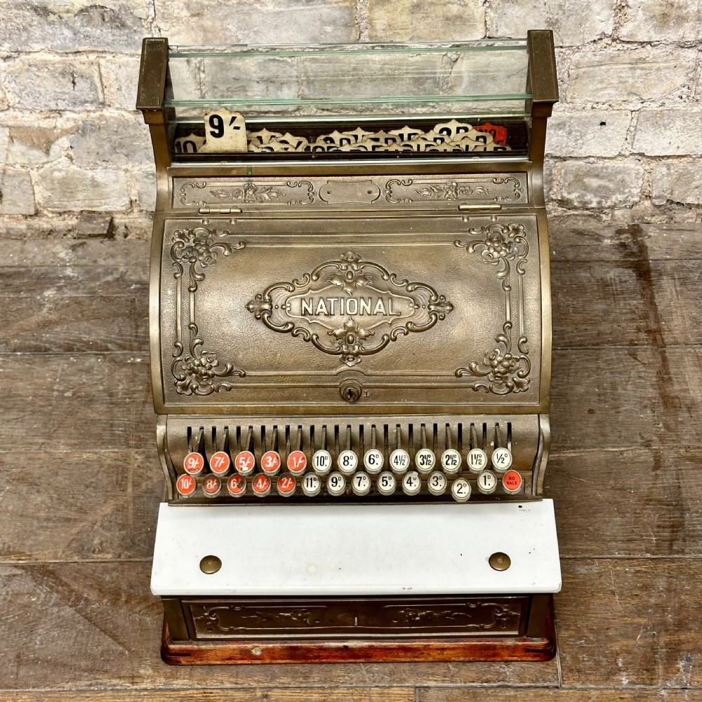 An ornate antique brass National cash register featuring a marble shelf, glass indicator top, and detailed relief scrolls. View II