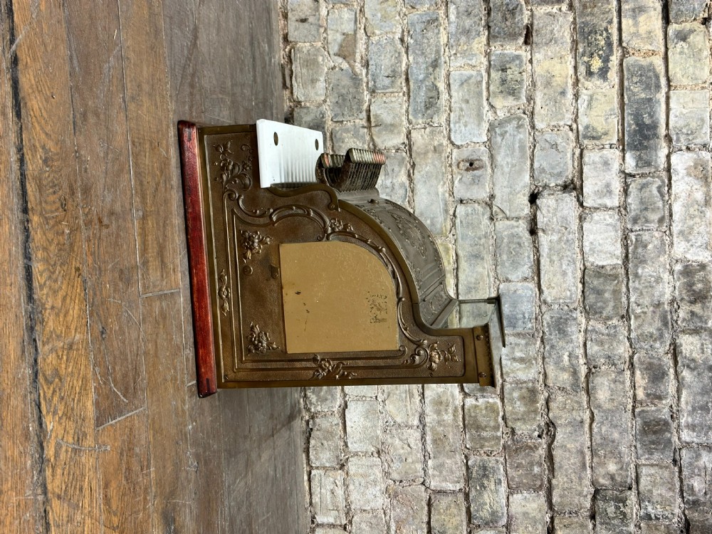 An ornate antique brass National cash register featuring a marble shelf, glass indicator top, and detailed relief scrolls. View III