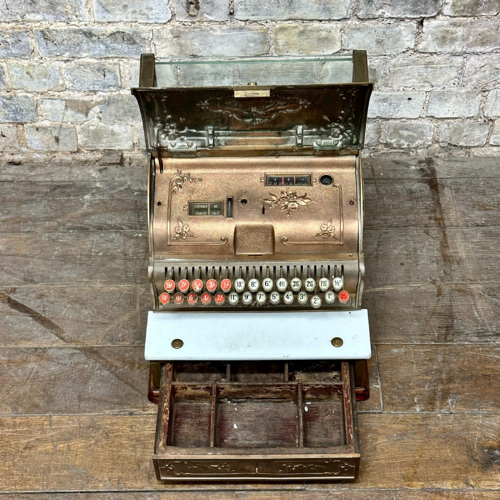 An ornate antique brass National cash register featuring a marble shelf, glass indicator top, and detailed relief scrolls. View V