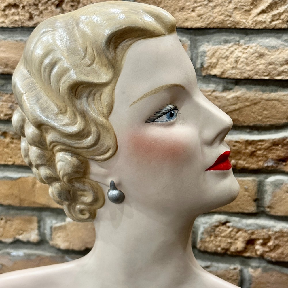 An Art Deco female mannequin bust featuring sculpted blonde waved hair, painted makeup, and a black circular stand. View III
