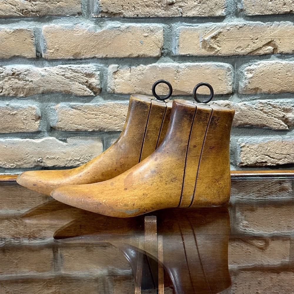 A pair of carved wooden boot trees with iron ring pull handles standing side by side. View II