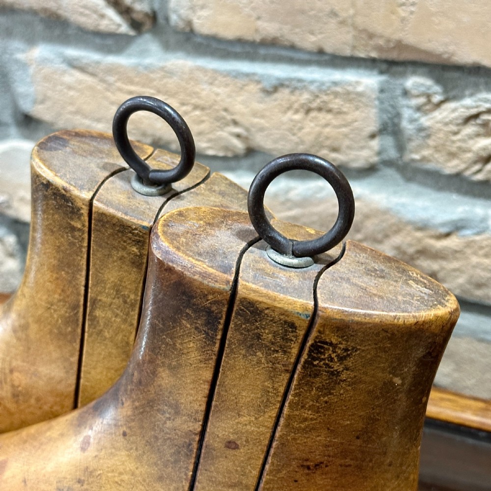 A pair of carved wooden boot trees with iron ring pull handles standing side by side. View III