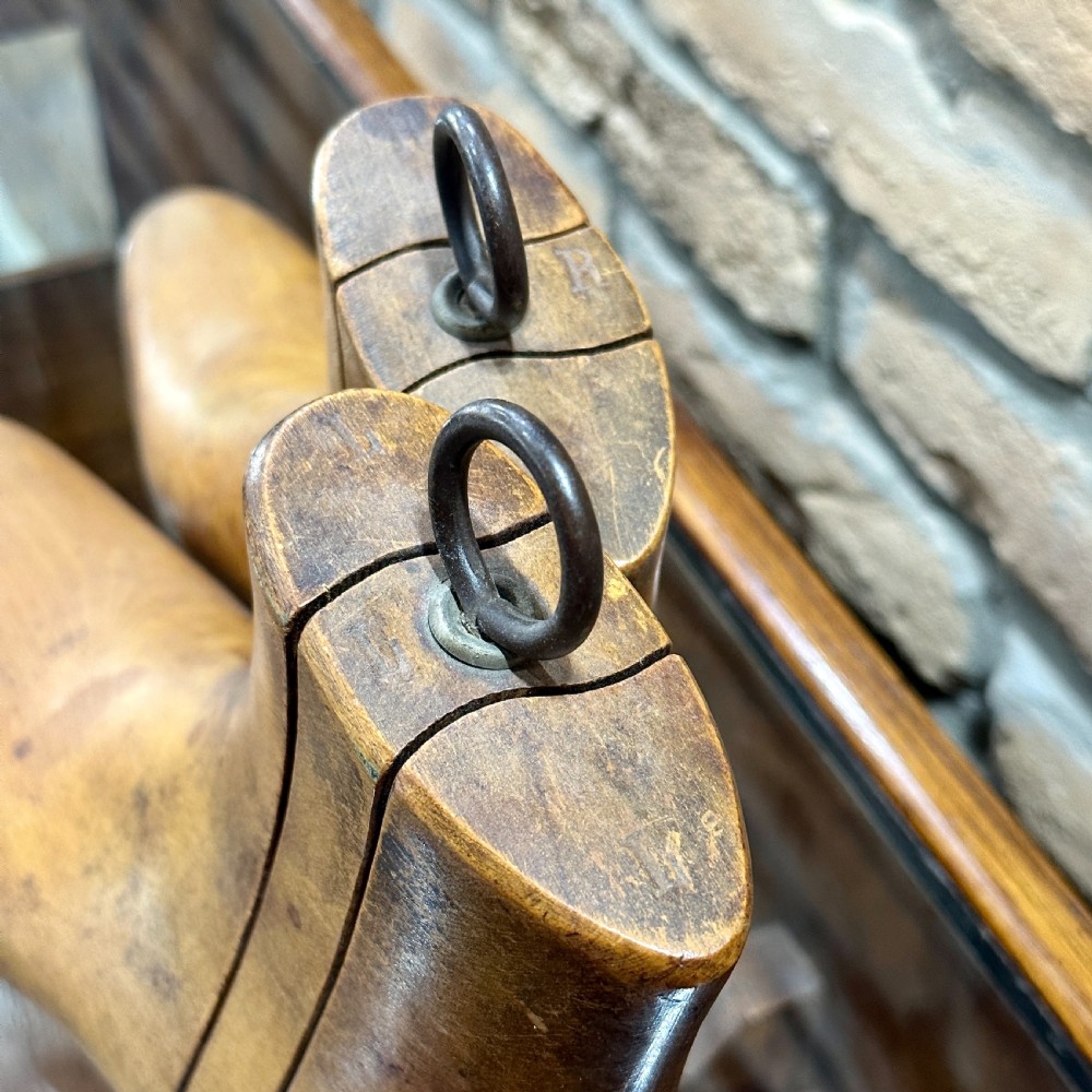 A pair of carved wooden boot trees with iron ring pull handles standing side by side. View IV