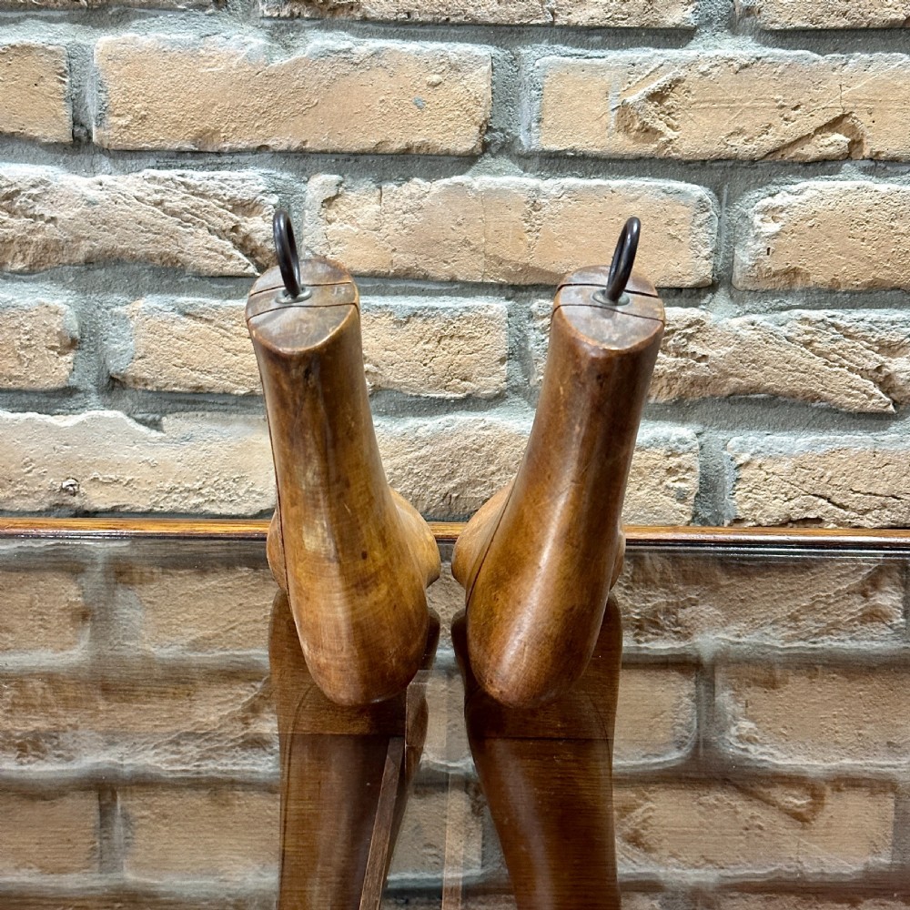 A pair of carved wooden boot trees with iron ring pull handles standing side by side. View V