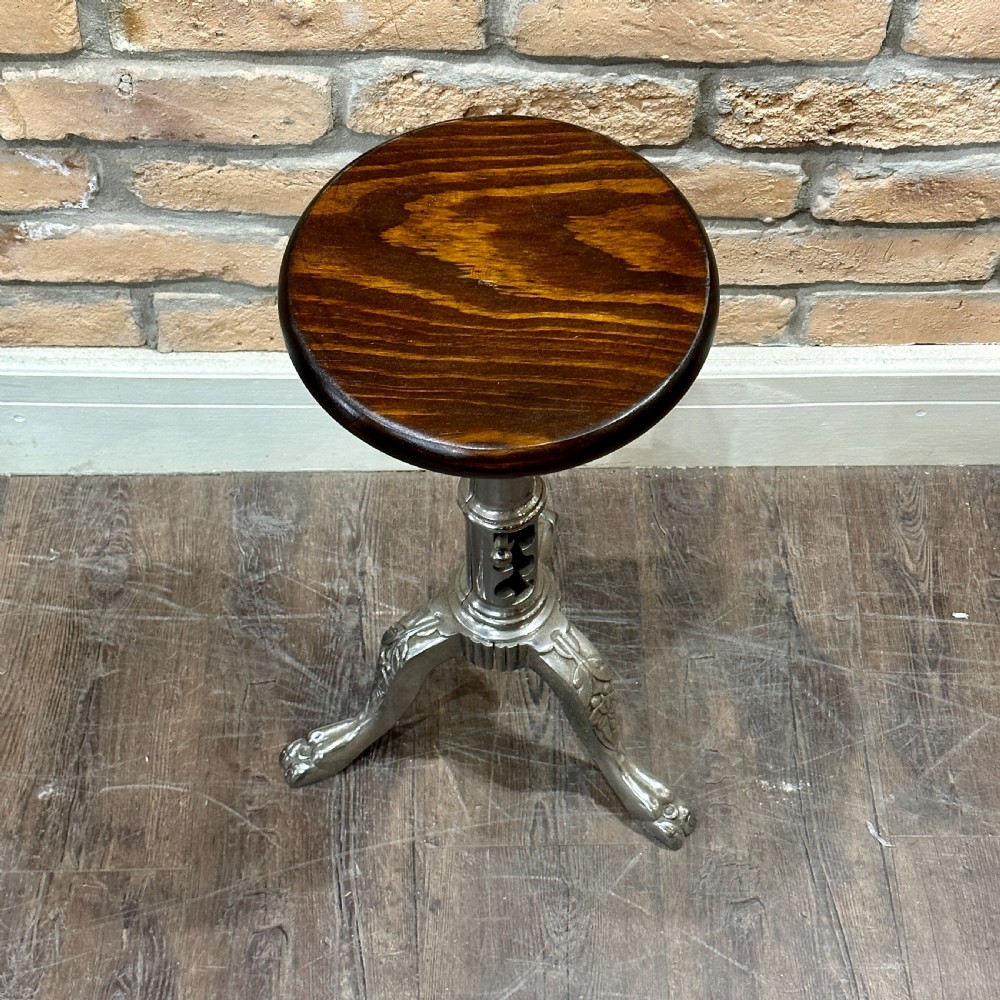 A Victorian industrial style height-adjustable stool featuring a dark round wooden seat resting on a silver-coloured cast metal tripod stem with ornate claw feet. View II