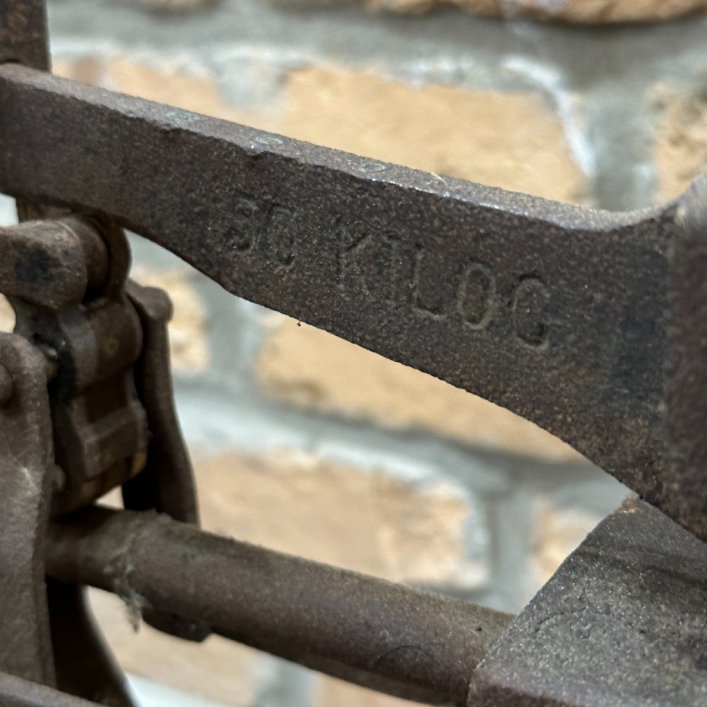 An antique floor platform scale featuring a wooden base, metal platform, and an exposed cast iron mechanical weighing arm. View IV
