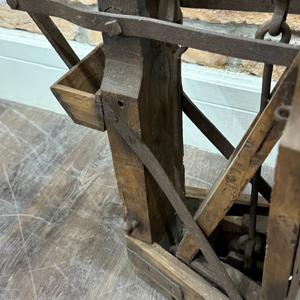 An antique floor platform scale featuring a wooden base, metal platform, and an exposed cast iron mechanical weighing arm. View V