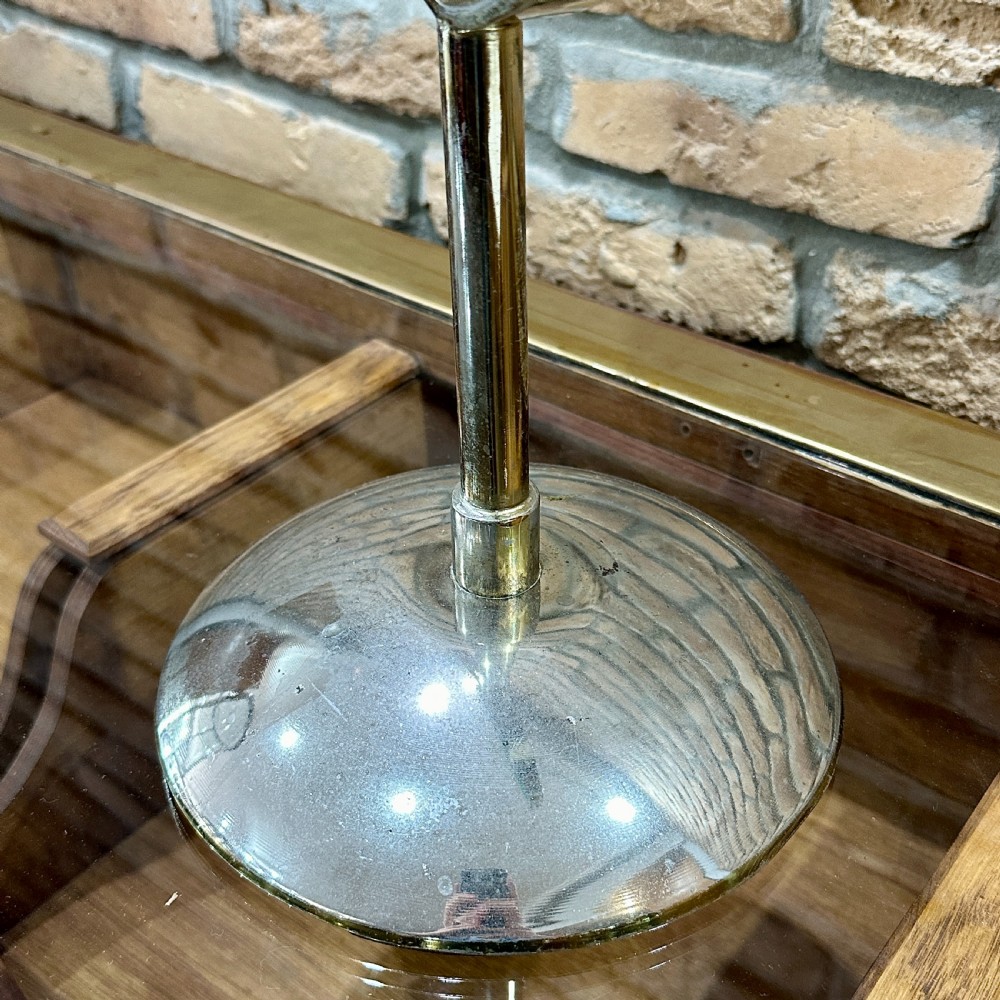 An Art Deco chrome vanity mirror featuring an oval glass frame supported by a central pedestal and circular dome base. View II