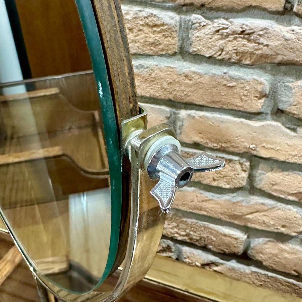 An Art Deco chrome vanity mirror featuring an oval glass frame supported by a central pedestal and circular dome base. View III