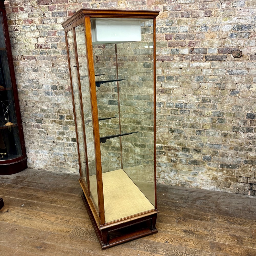A tall glazed mahogany shop display cabinet featuring double glass doors, side glass panels, and internal metal shelf brackets on a plinth base. View II